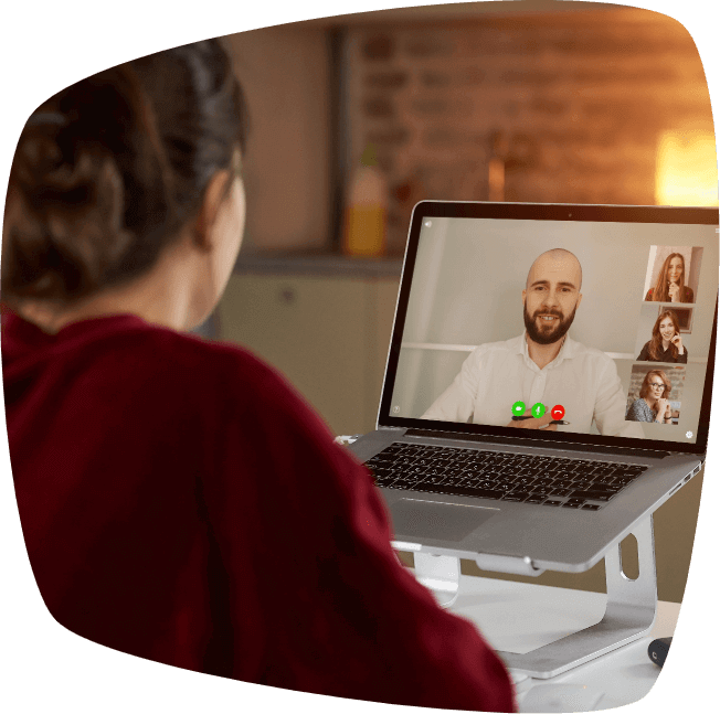back view of female employee who is working remotely talking to her colleague about business in video conference on laptop at home
